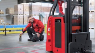 Linde MH töötaja põlvitab L-MATICi ees ja kontrollib, kas kõik on korras.