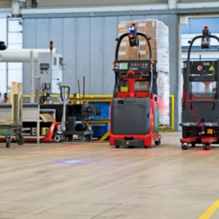 Kaks automaatset kõrglaotõstukit L-MATIC veavad kaupa pakkimisliini ja läbivoolulao vahel.